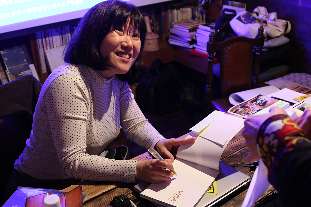 お客さんが購入した写真集にサインをする著者の石井陽子さん。著者と直接触れ合えるのもイベントの魅力の1つ